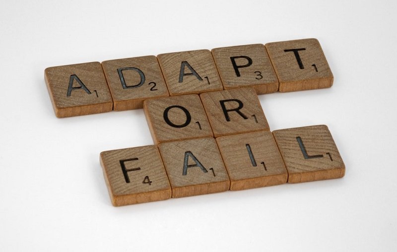A white table with Scrabble tiles spelling out "Adapt or Fail," representing the need for businesses to be flexible in order to scale.